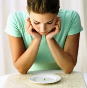 woman looking at a pea on a plate